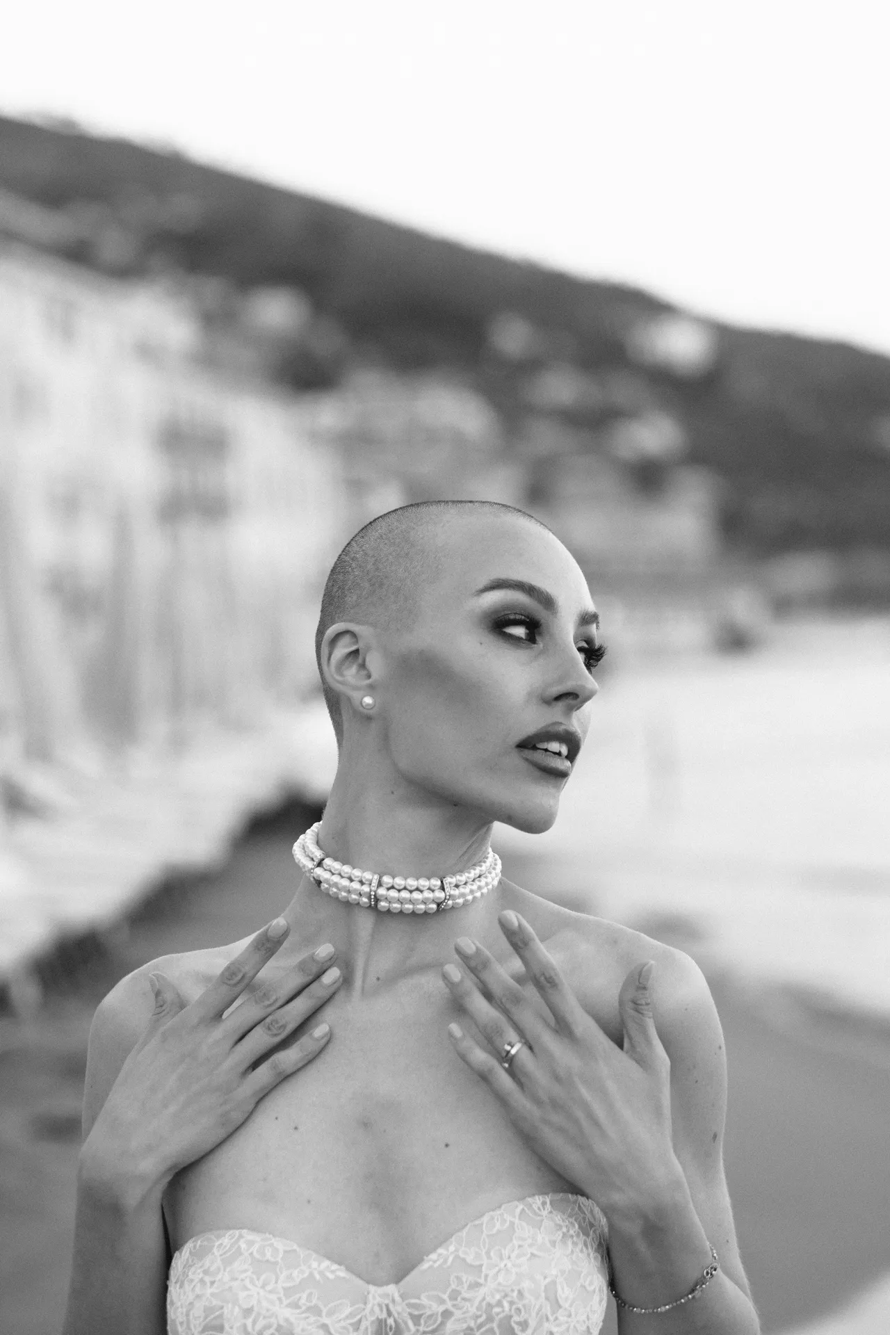 Donna con collana di perle e le mani appoggiate sul petto, in bianco e nero
