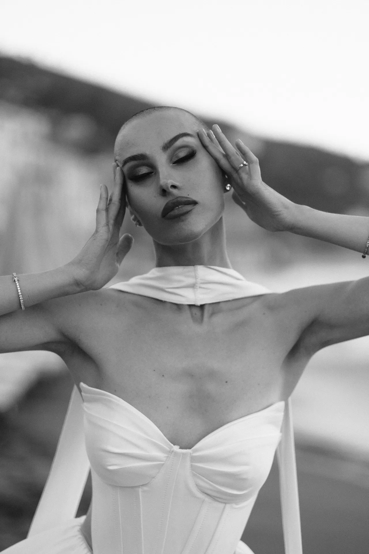 Donna con le mani alle tempie e gli occhi socchiusi, corsetto bianco