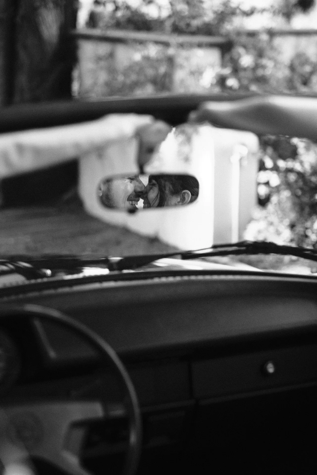 Gli sposi riflessi nello specchietto retrovisore di un'auto d'epoca, il cruscotto in primo piano