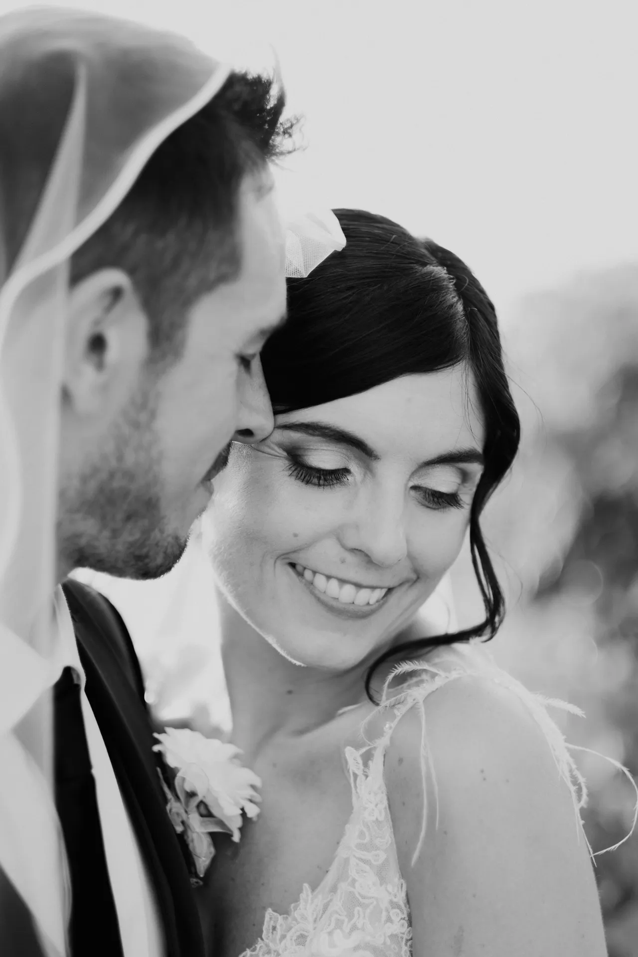 La sposa sorride guardando in basso mentre lo sposo la osserva da vicino